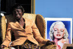 JUHAN KUUS. Woman at the Paarden Eiland flea market with a Marilyn Monroe poster. Cape Town, South Africa. 2006